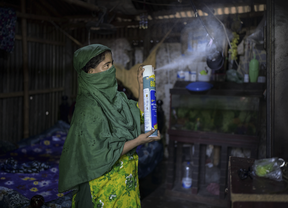 Masuma uses insecticide spray to try to prevent mosquitoes from entering her home in Mirpur, Dhaka. Her child is suffering from dengue. The locality is badly affected, with many households with someone who has contracted the disease.