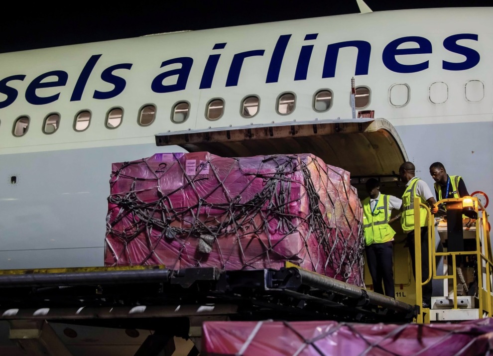 Airline workers unloading a package of vaccines from an airplane.