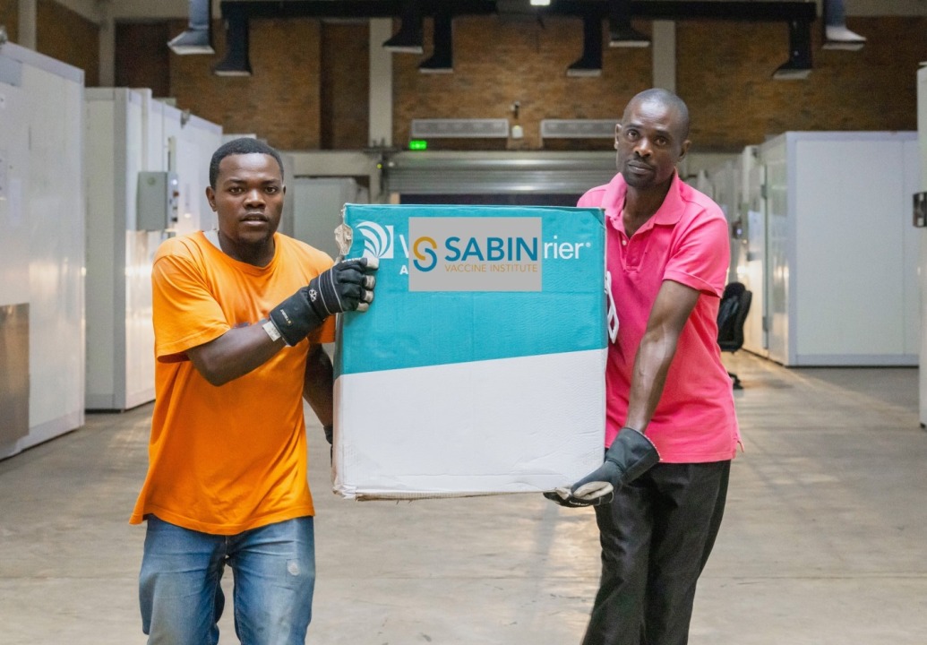 Two men carry a box of Sabin Marburg vaccines