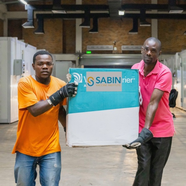 Two men carry a box of Sabin Marburg vaccines